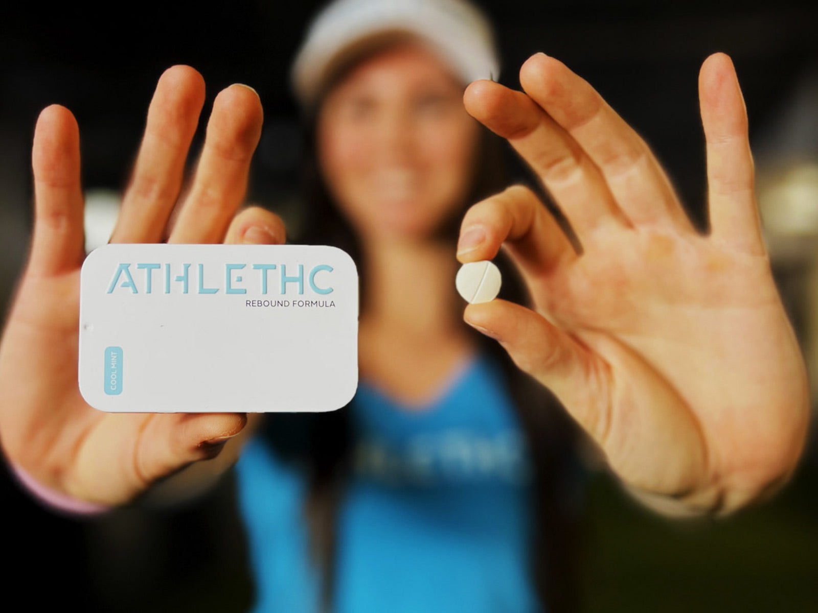 Woman holding a tin of mints in one hand and a small mint in her other hand