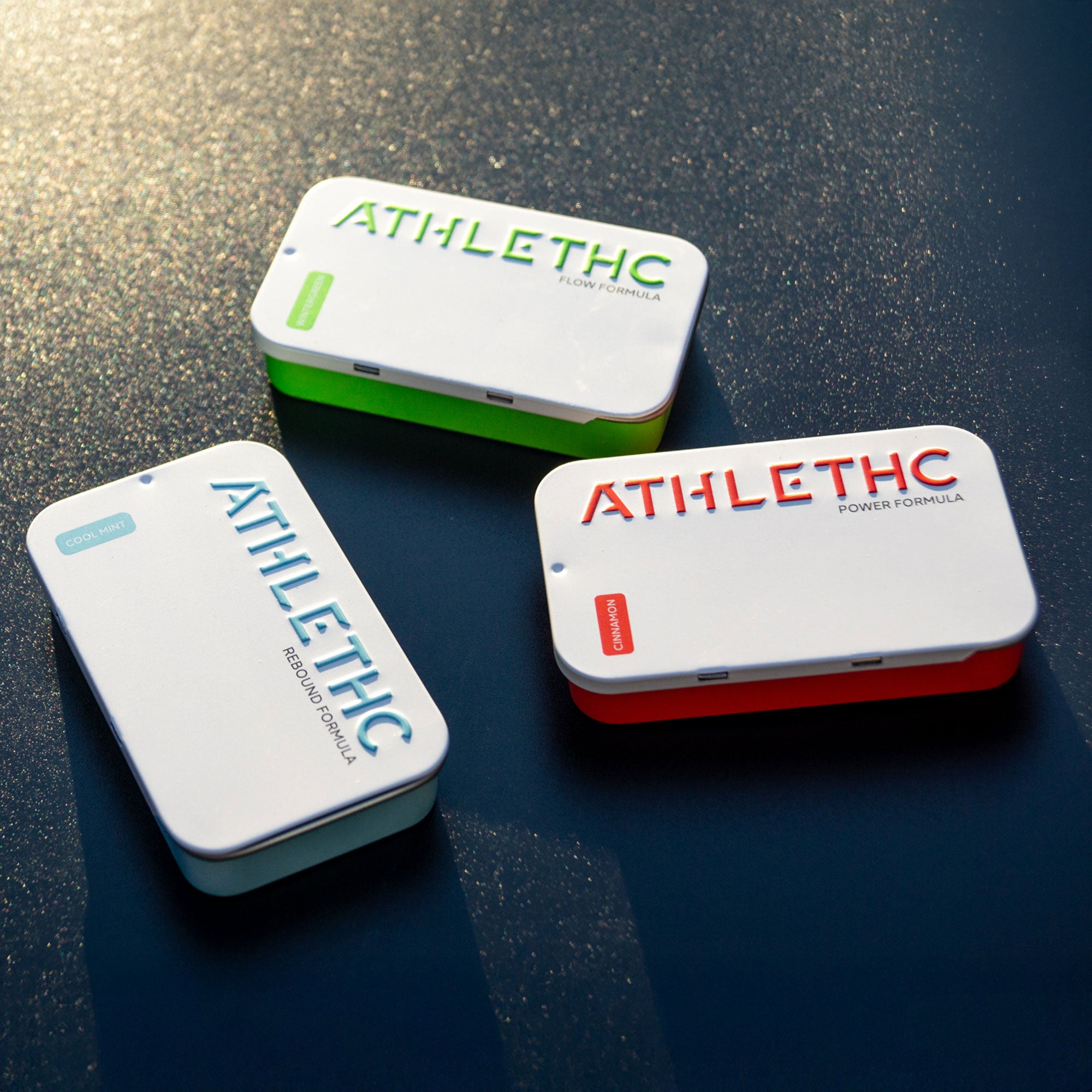 Three 'ATHLETHC' containers on a reflective surface