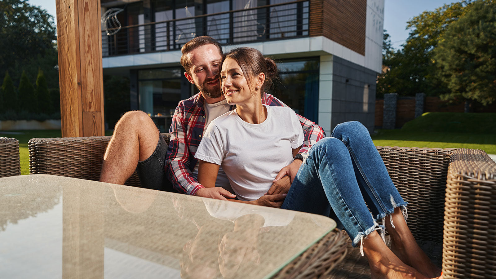 Couple sitting on a patio table outdoors, smiling at each other.