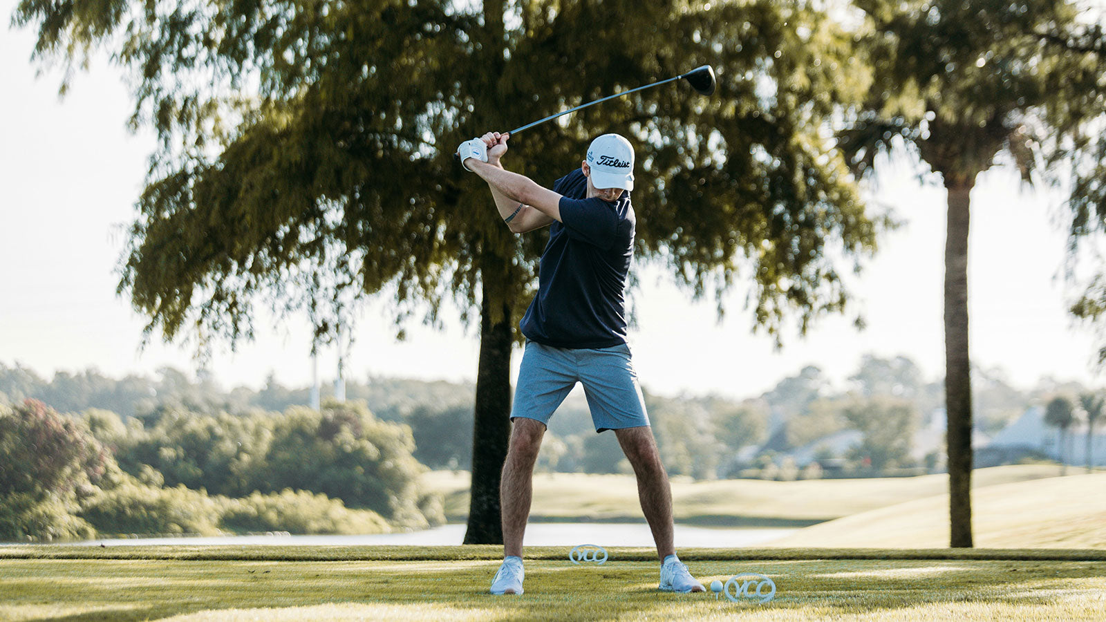 Person playing golf on a course with trees and greenery in the background while taking ATHLETHC Microdose THC mints for golfing