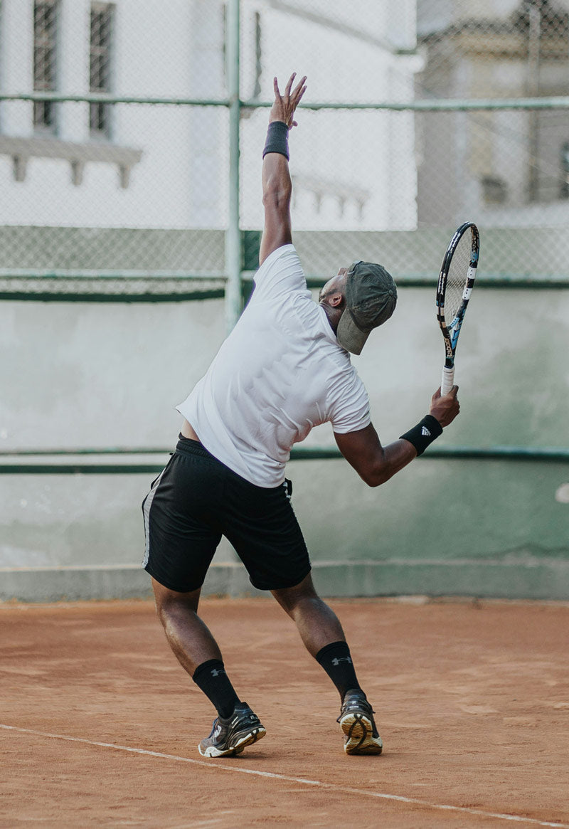 Person playing tennis on a clay court with a racket